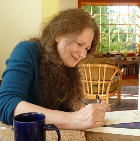 Jane Hirshfield writing at table.