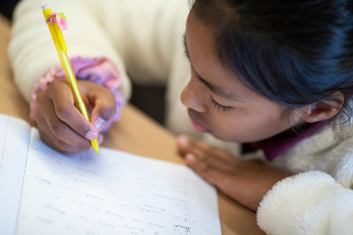 young girl writing with pencil and paper